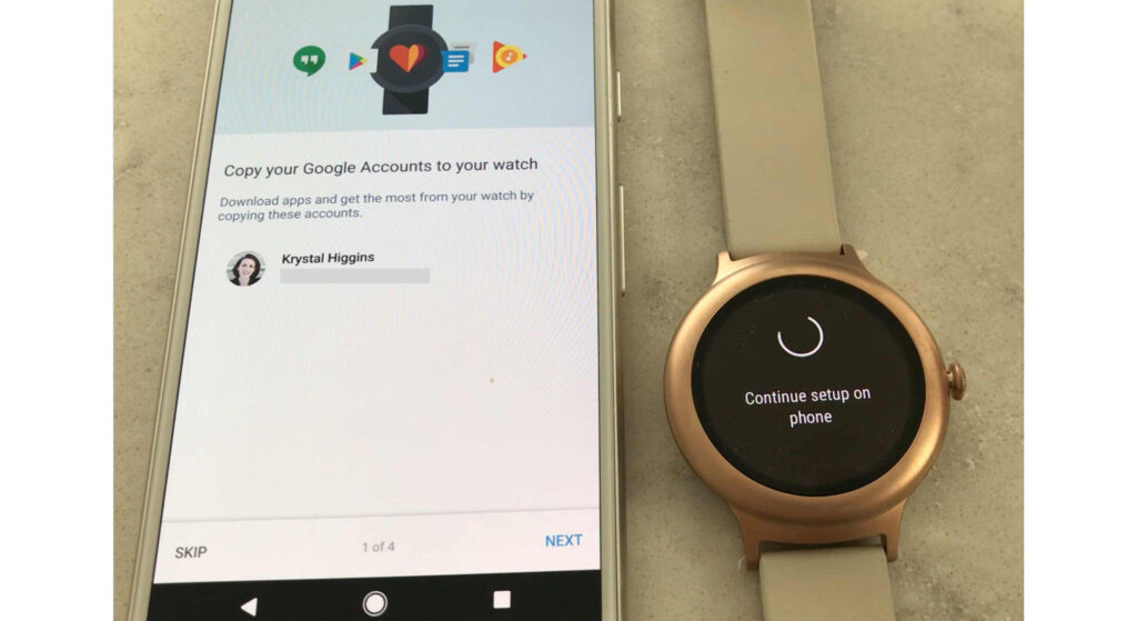 Photograph of phone with Wear OS setup on it, next to a smartwatch that says "continue setup on your phone"